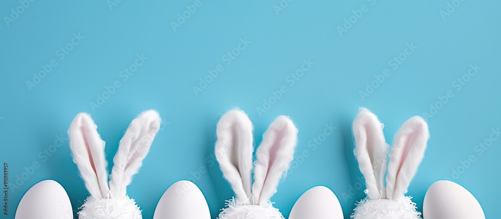 Poster easter themed image with bunny ears and white eggs set against a blue backdrop perfect for a copy sp
