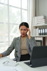 Asian woman, independent businesswoman, feeling stressed, achy, and sleepy while working on a laptop. Tired Asian businesswoman has a headache at the office Feeling sick at work.