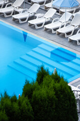 swimming pool with sun beds and blue water.