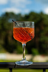 glass of orange cocktail with a lemon and ice