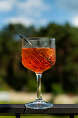 glass of orange cocktail with a lemon and ice