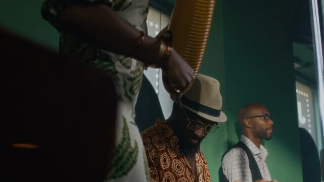 Tilt down view of African American female musician dancing with guiro while rehearsing song with male bandmates playing conga and drums in studio