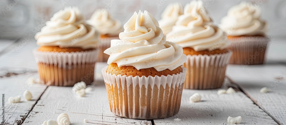 Poster Vanilla cupcakes with cream cheese frosting displayed on a white wooden surface with selective focus and copy space image