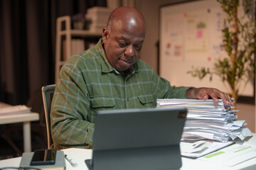 Retired businessman, personal business is checking, checking documents, searching for financial reports. Analyze online data in the office Sitting at the desk in front of the laptop.