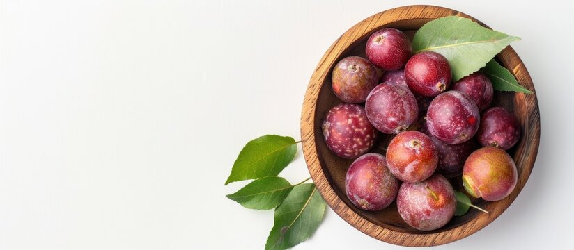 Ripe phalsa fruit in a wooden bowl with leaves isolated on a white background emphasizing a top view with selective focus and copy space image