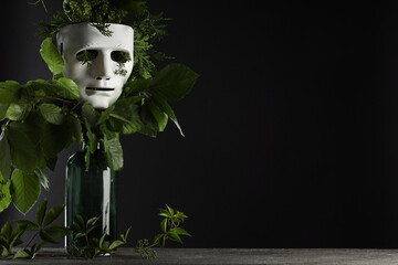 Theatrical performance. Plastic mask and floral decor on table against black background, space for...