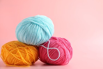 Different colorful yarns on pink background, closeup. Space for text