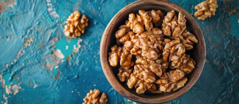 Poster walnut kernel halves arranged attractively in a wooden bowl captured from above on a colored backgro
