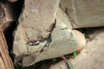 A large rock with a crack in it. The crack is long and deep. The rock is grey and rough