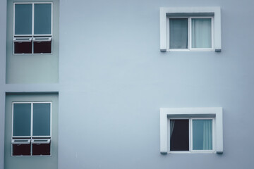 The building has two windows on each side. The windows are open and the curtains are drawn. The building is white and has a modern look