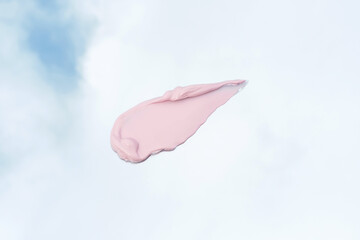 Pink cosmetic clay smear against the background of sky with clouds close-up.