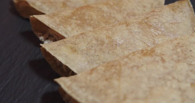 Beautiful slow motion zoom out shot of a set of chicken enchiladas with Mexican fried tortilla inside a restaurant kitchen with natural light.