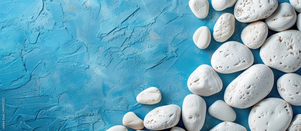 Aufkleber a messy arrangement of white textured pebbles on a blue table with copy space image