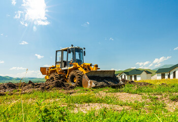 Heavy machine in a field in mountains construction site new cottage village building