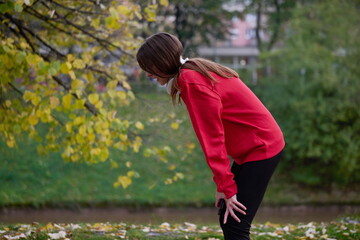 Athletic young woman taking a breath and relaxing after jogging and stretching. Woman Training and Workout Exercises On Street.