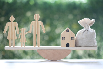 Model family and model house with money bag on wood scale seesaw on natural green background,Save...
