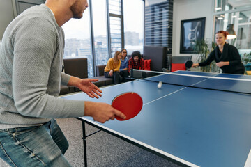  Business colleagues take a break from work to enjoy a game of table tennis, fostering teamwork and camaraderie in the workplace