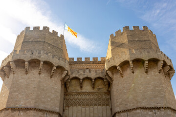 The Valencian Community flag waving in the wind. Torres de Quart, medieval building in Valencia,...