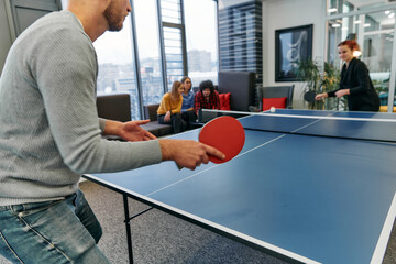  Business colleagues take a break from work to enjoy a game of table tennis, fostering teamwork and camaraderie in the workplace