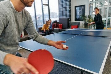  Business colleagues take a break from work to enjoy a game of table tennis, fostering teamwork and...