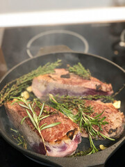 steak with rosemary and garlic on a frying pan in the kitchen