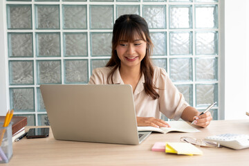 Young woman engages in online study at workspace.