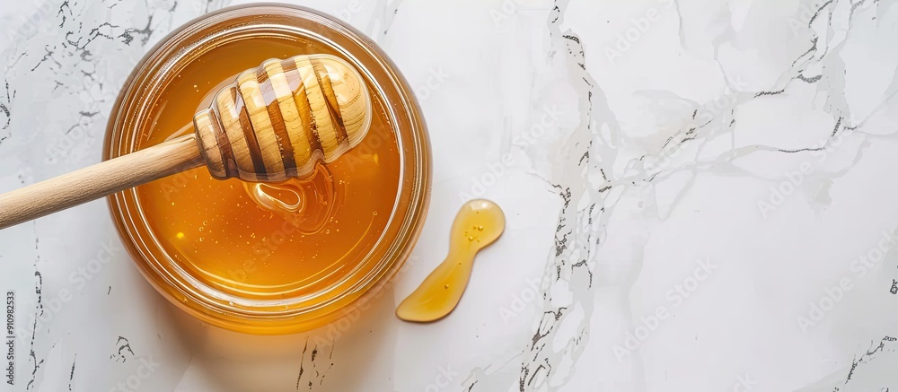 Poster A delicious honey jar with a wooden honey dipper placed on a white surface captured from above with room around for text in the image. copy space available