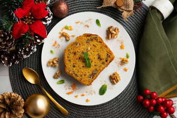 Delicious piece of carrot cake with walnuts on a table with christmas decorations.