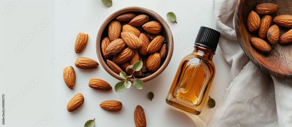 Poster a jar of almond oil placed near a bowl of almonds on a white background viewed from the top creating