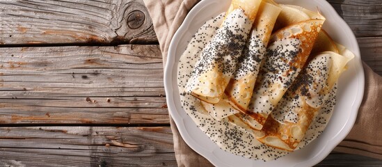 Delectable poppy seed crepes blinis with creamy sauce on a white plate against a wooden backdrop perfect for a copy space image