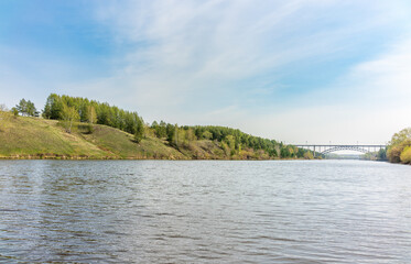 Pine trees and rocks on the river shore with fall foliage around