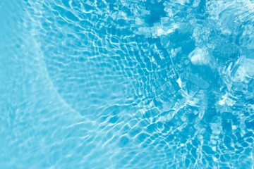 Blue water with ripples on the surface. Defocus blurred transparent blue colored clear calm water surface texture with splashes and bubbles. Water waves with shining pattern texture background.
