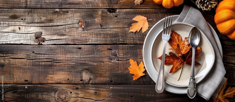 Poster autumn themed plate silverware in a napkin with fall decor on a wooden background ideal for thanksgi