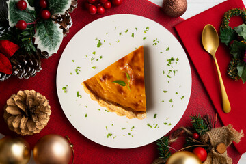 Delicious piece of American pumpkin pie in an overhead view on a table with christmas decoration.