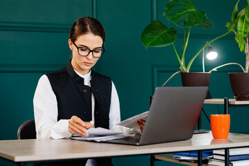 Stylish young woman working on a laptop in a modern office. Perfect for concepts of productivity, business, and contemporary work environment.