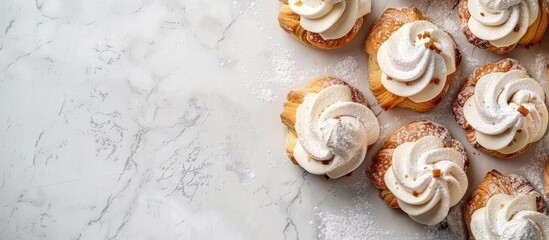 Obraz premium Homemade profiteroles topped with cream and powdered sugar on a white stone backdrop with copy space; a delightful dessert.