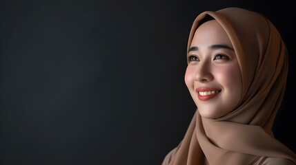 Portrait of a beautiful smiling malay Asian woman in a hijab looking away isolated on a dark background, in the style of copy space concept, in black gold theme.