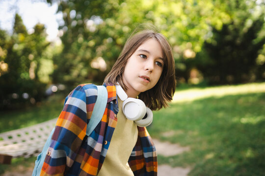 Contemplative teenage boy with wireless headphones at park