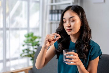 A woman is taking a pill and drinking water