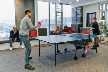  Business colleagues take a break from work to enjoy a game of table tennis, fostering teamwork and camaraderie in the workplace