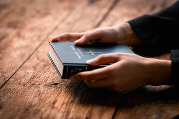 Hands folded in prayer on a Holy Bible in church concept for faith, spirituality and religion, woman praying on holy bible in the morning. woman hand with Bible praying.