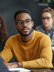 Obraz premium A person wearing a bright yellow sweater sits at a wooden table with a calm expression