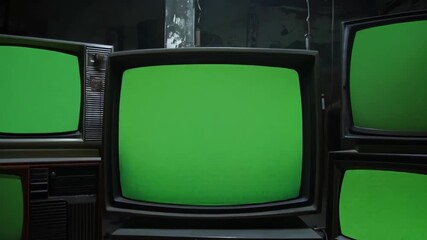 Vintage televisions with green screens in a dark room