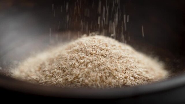 Medicinal isabgol or psyllium husks falling in slow motion into a brown wooden bowl close up