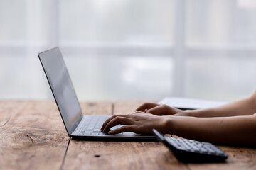 Close up of female hands while typing on laptop use calculator accountant 