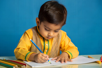 Young Boy Drawing with Color Pencils in Traditional Clothes Against Blue Background
