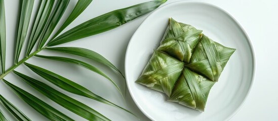 Obraz premium Top view of ketupat or rice dumplings displayed on a white ceramic plate with ample copy space image available