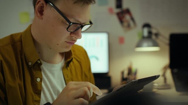 Remote work. An experienced specialist peers intently into a tablet display, creating AI algorithms. A professional systematically works on a tactile device in a comfortable home environment