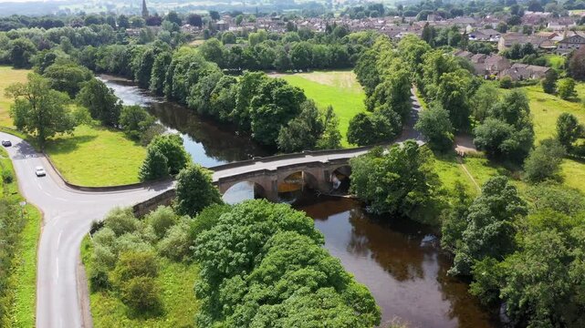 Aerial footage of the beautiful town of Masham, Ripon in North Yorkshire in the UK showing the British countryside town from above and a bridge going in to the village in the summer time
