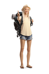 Happy female tourist with a backpack gesturing thumbs up